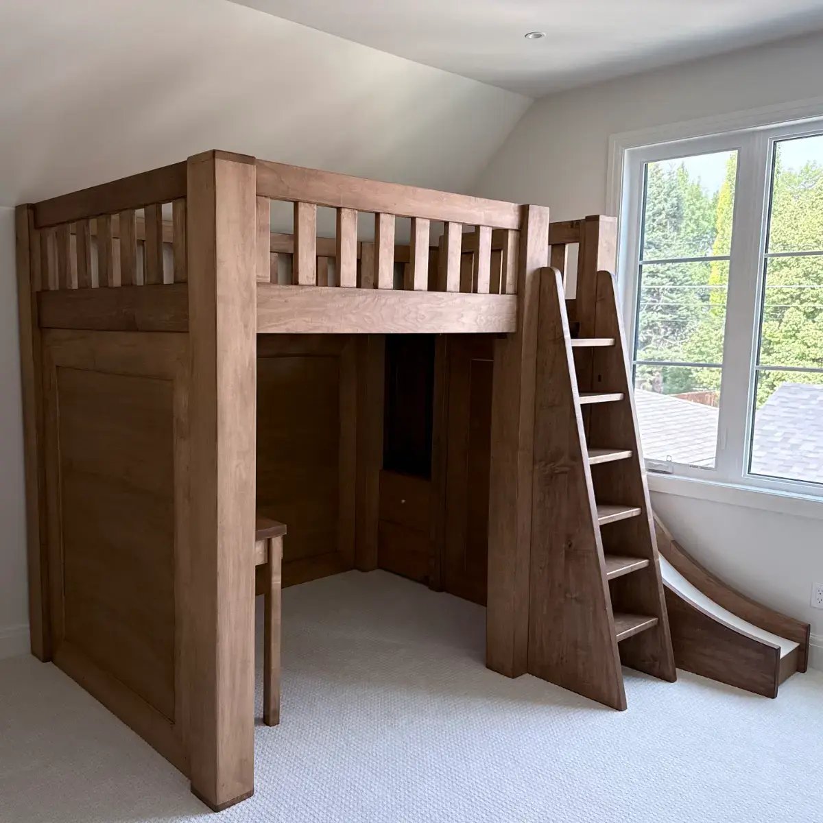 Custom solid maple loft bed with integrated slide, built-in desk and storage stairs, built for a boys' bedroom in Calgary
